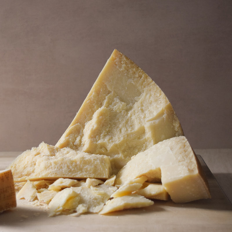 Closeup of a man slicing a Parmigiano Reggiano cheese wheel Stock